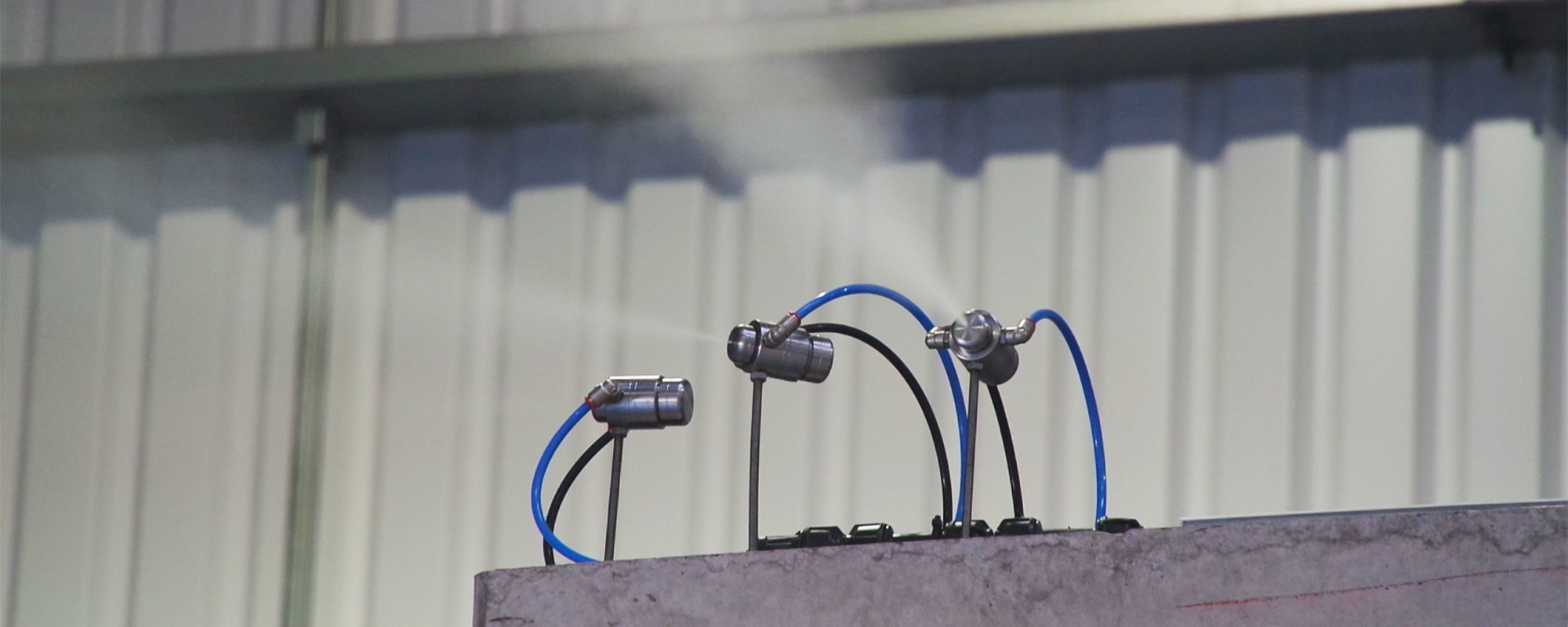 3 AtomisterAiro nozzles mounted on top of a wall spraying a very fine mist